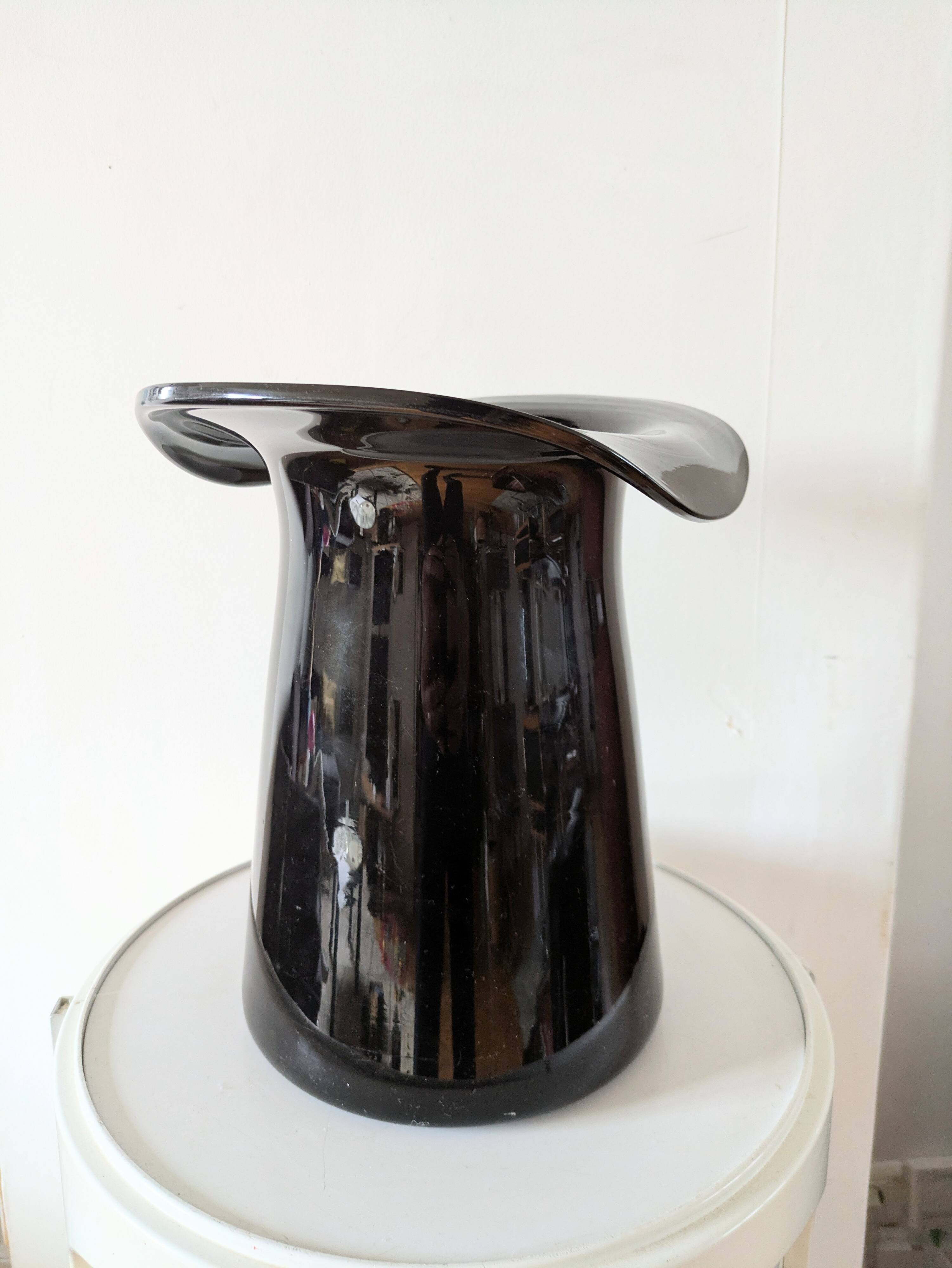 Large black glass vase topped with a 70s hat
