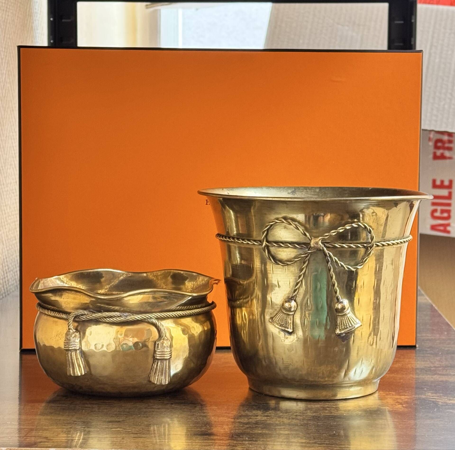 Pair of brass plant pots, decorated with cord and tassels.