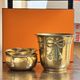 Pair of brass plant pots, decorated with cord and tassels.