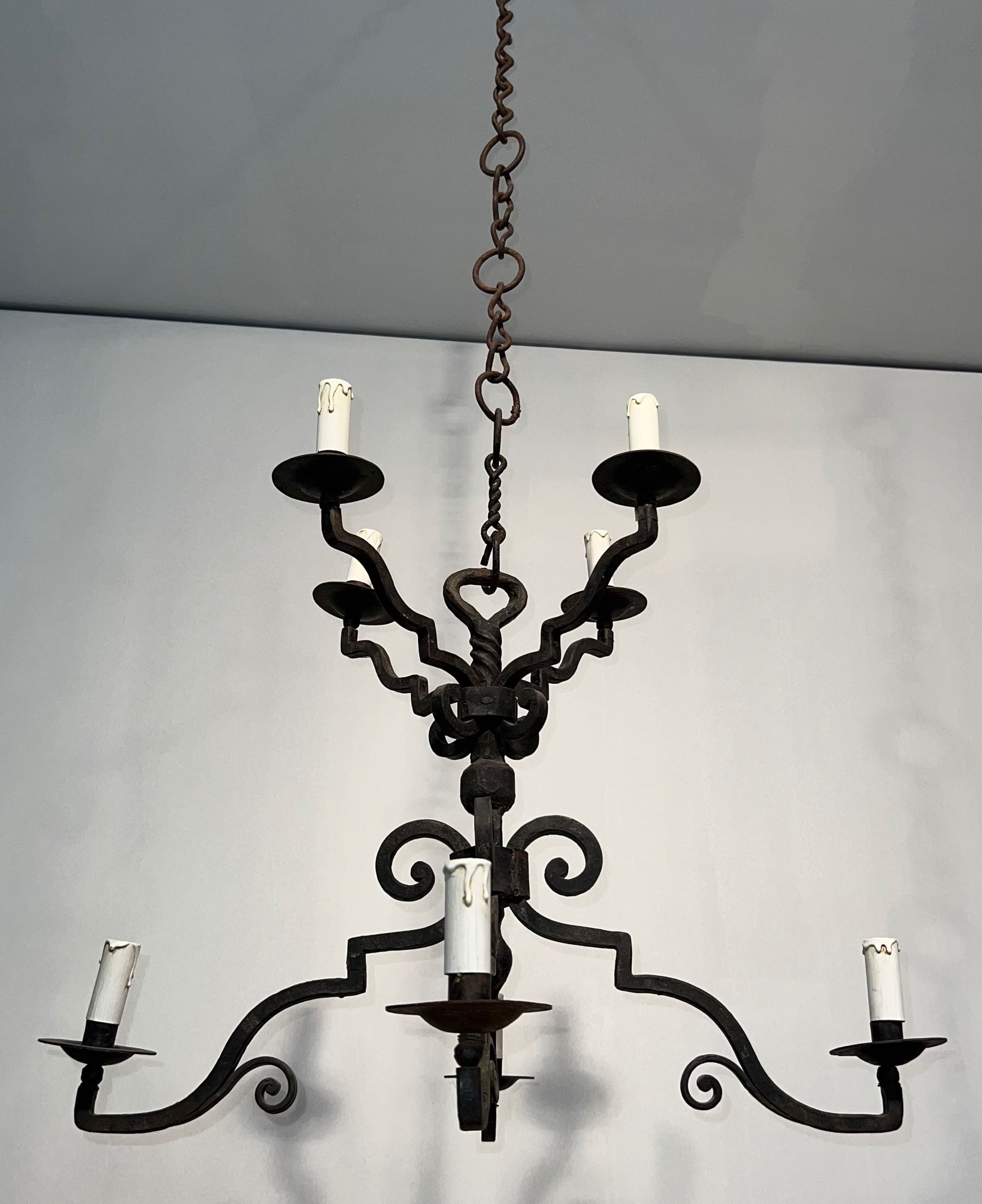 Two-tiered wrought iron chandelier with eight light arms in Gothic style.