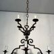 Two-tiered wrought iron chandelier with eight light arms in Gothic style.