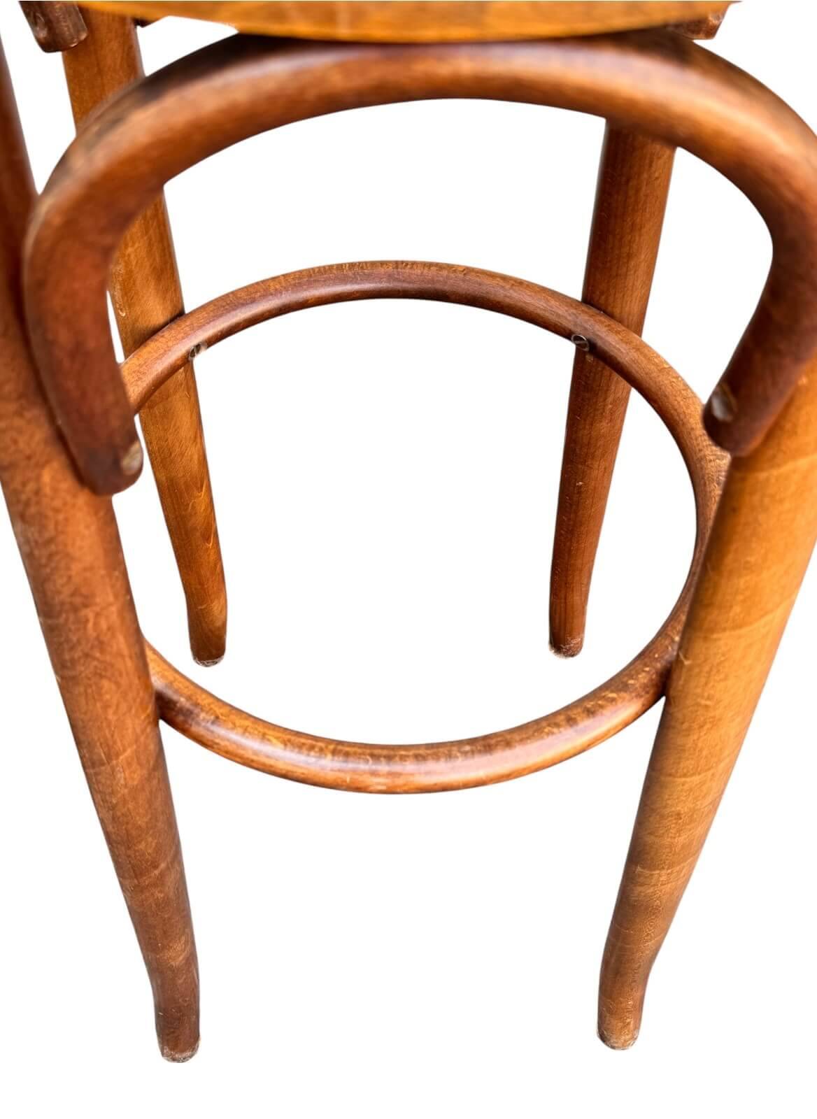 Old high stool in curved wood with caned seat