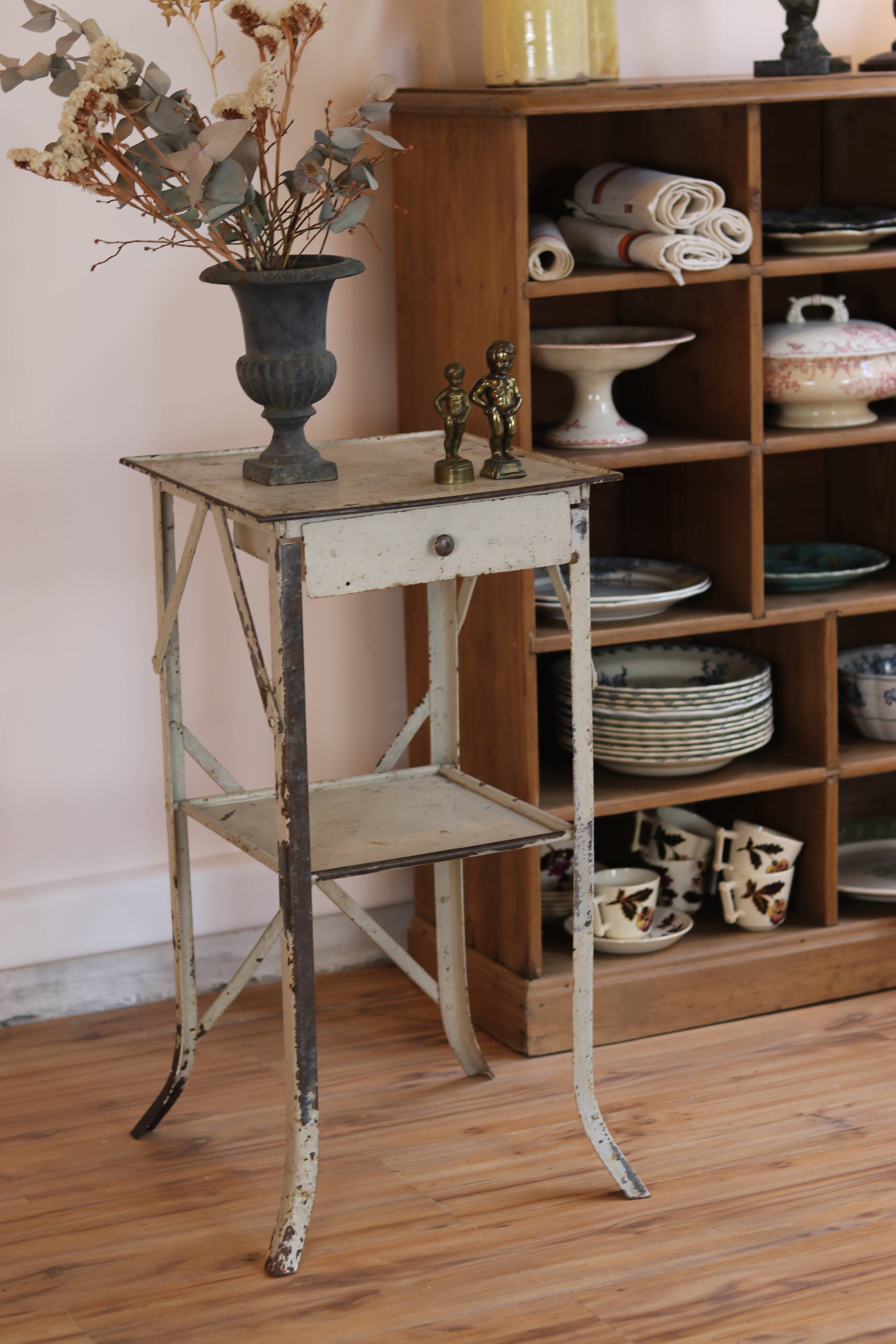 Painted metal side table, patinated white, with a drawer and two shelves