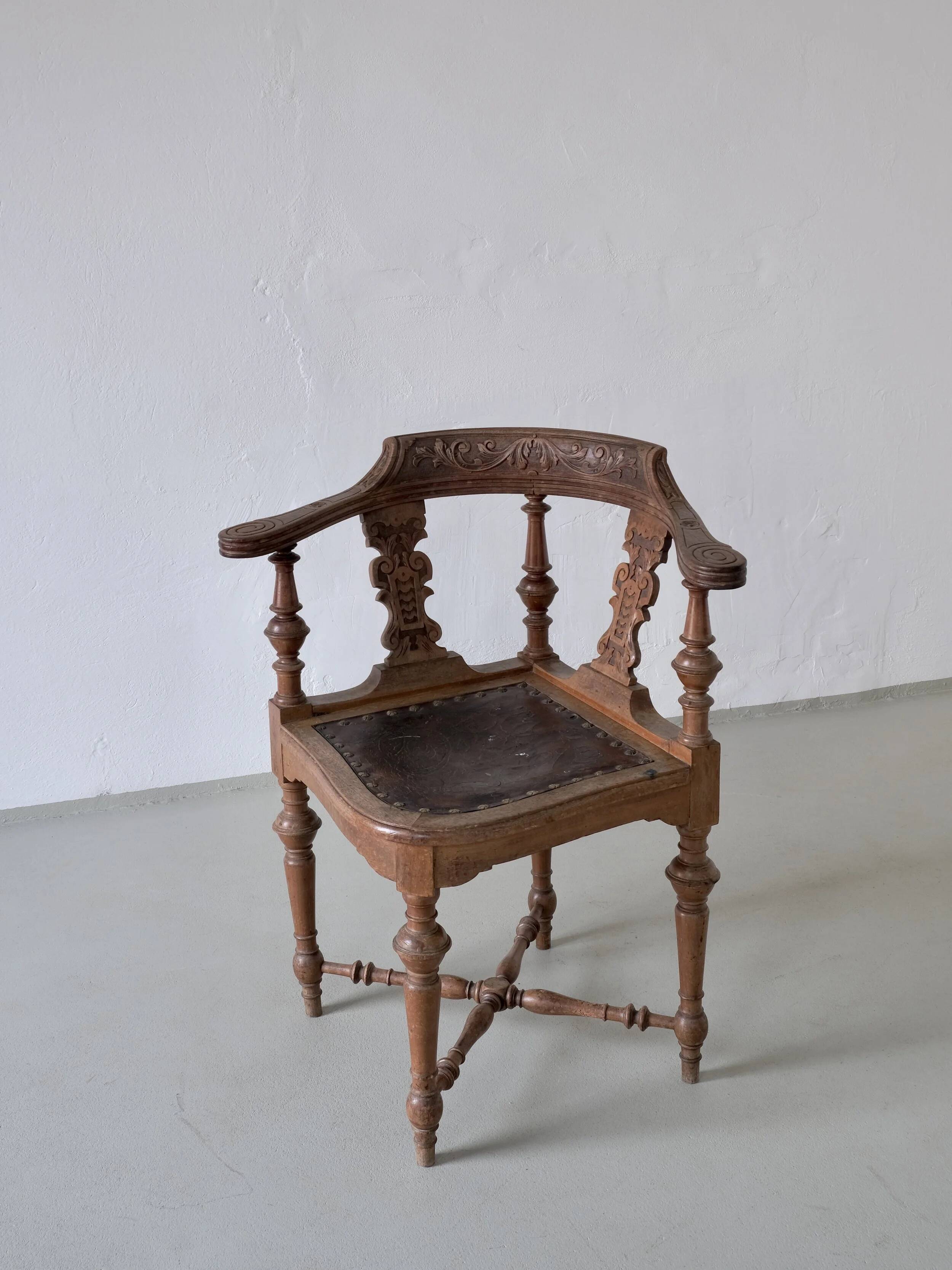 Fauteuil d'angle ancien sculpté avec assise en cuir