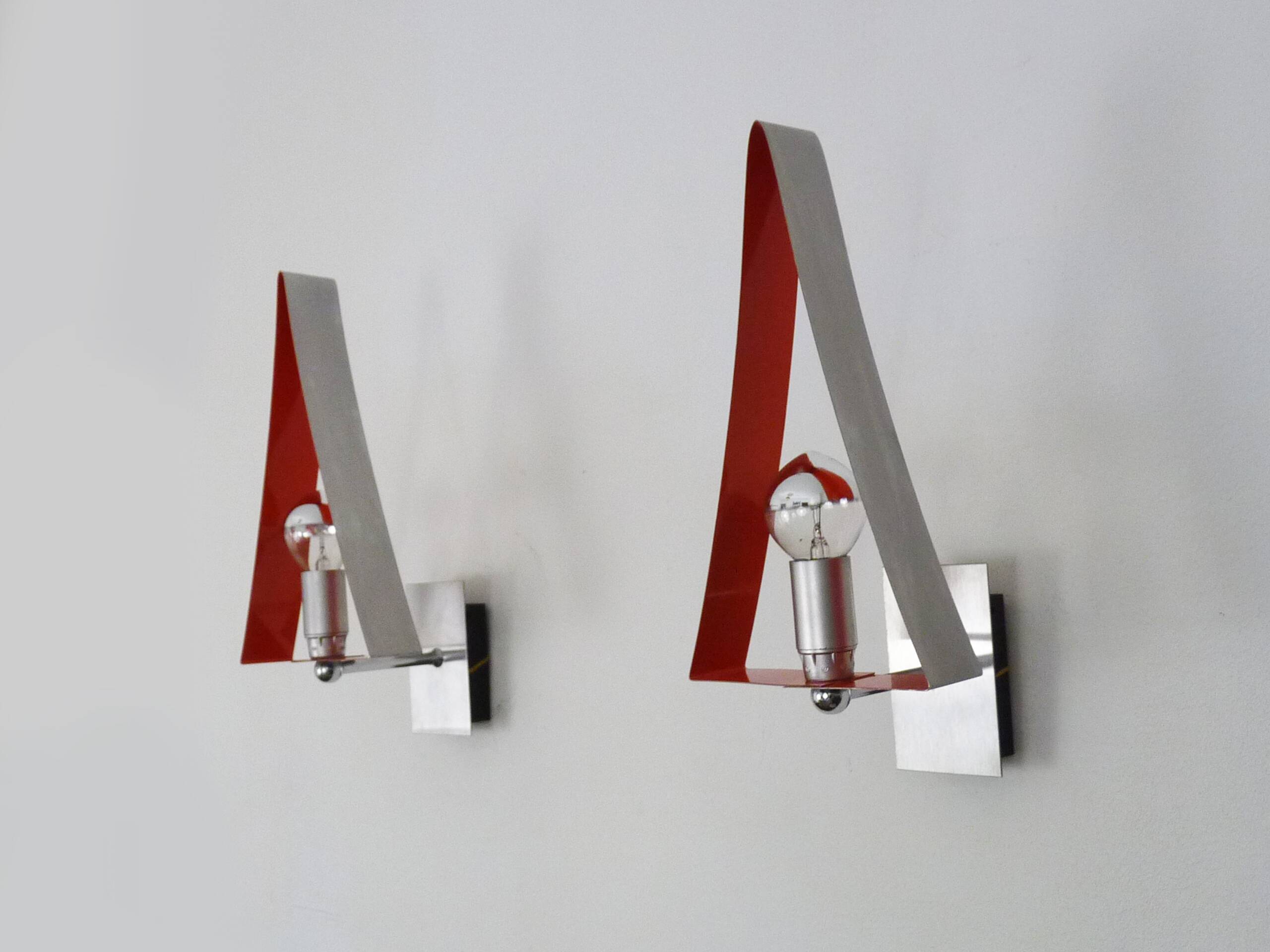 Pair of triangular wall sconces in chrome metal and orange. 1970s.