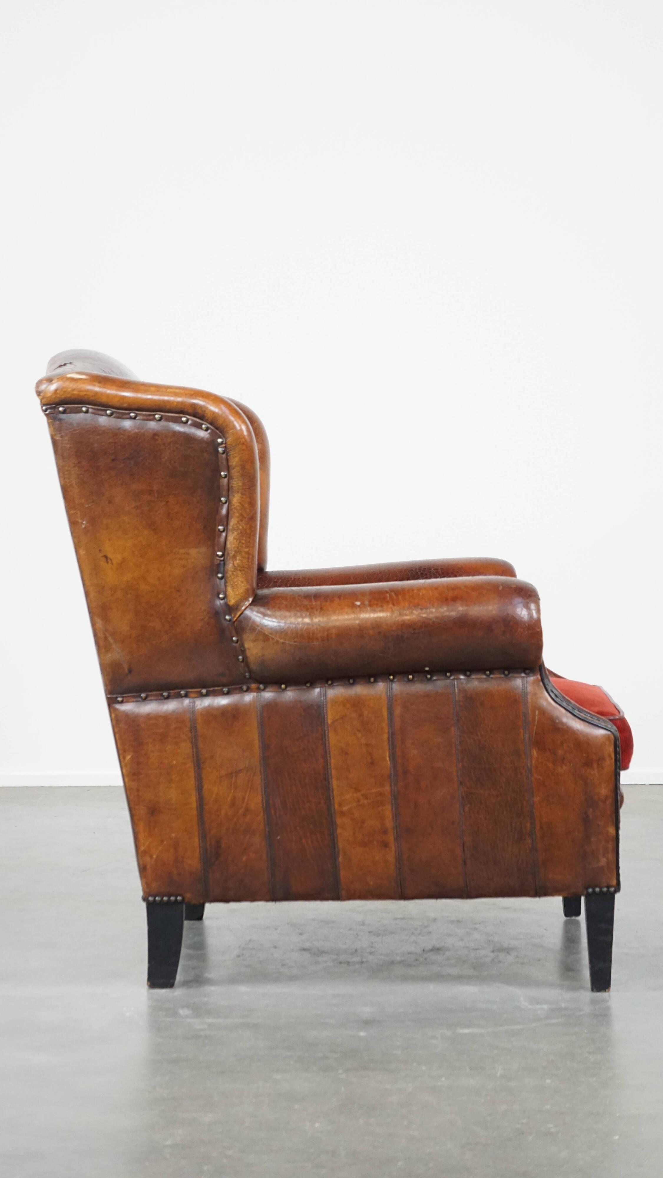 Sheepskin leather wingback chair with a red corduroy seat cushion
