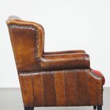 Sheepskin leather wingback chair with a red corduroy seat cushion