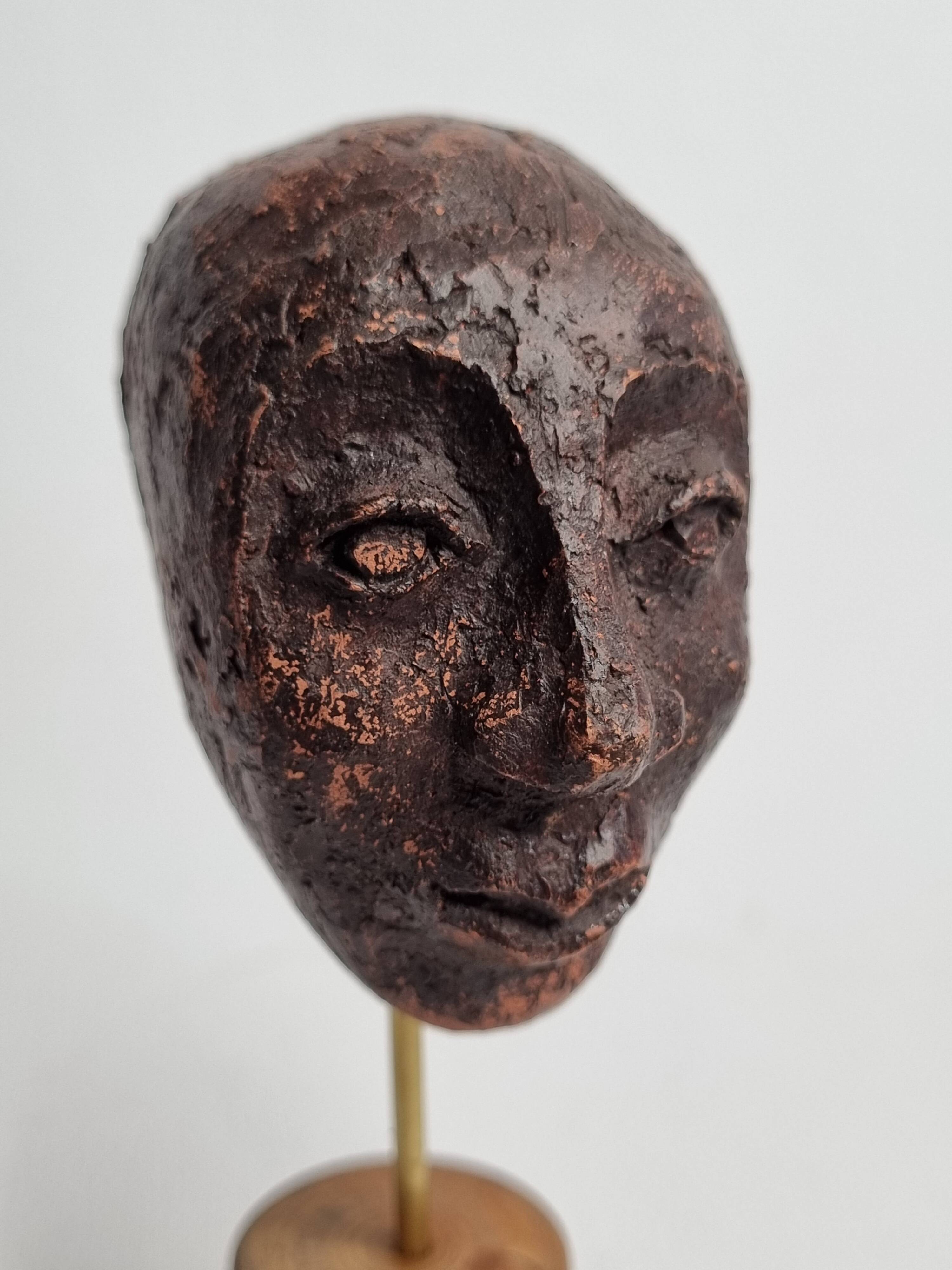 Expressive sculpted head in patinated terracotta on wooden base, 14 cm