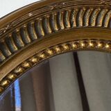Oval-shaped wooden mirror in gold color