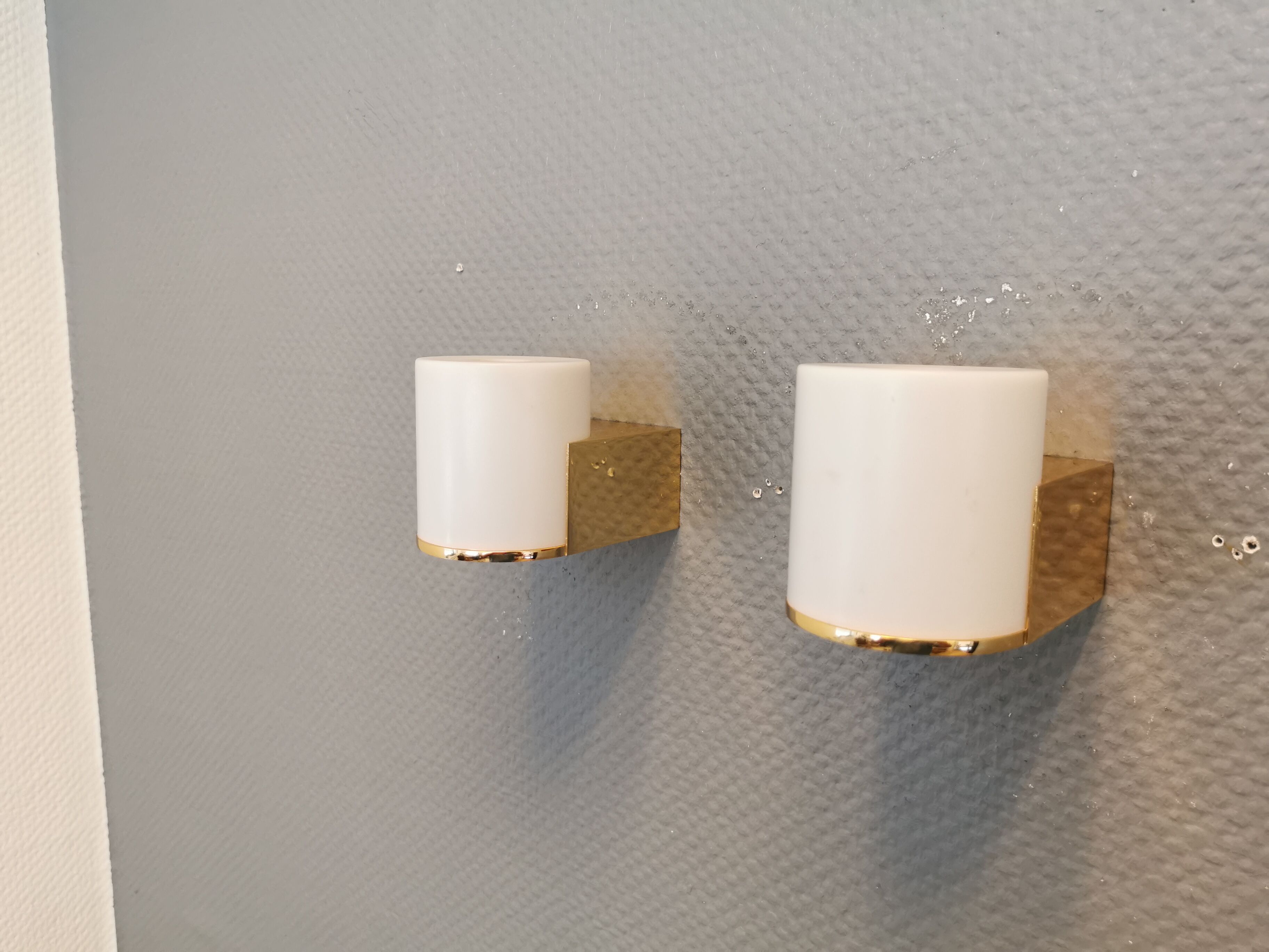 Wall lamps with milky white acrylic plastic shades and solid brass bases