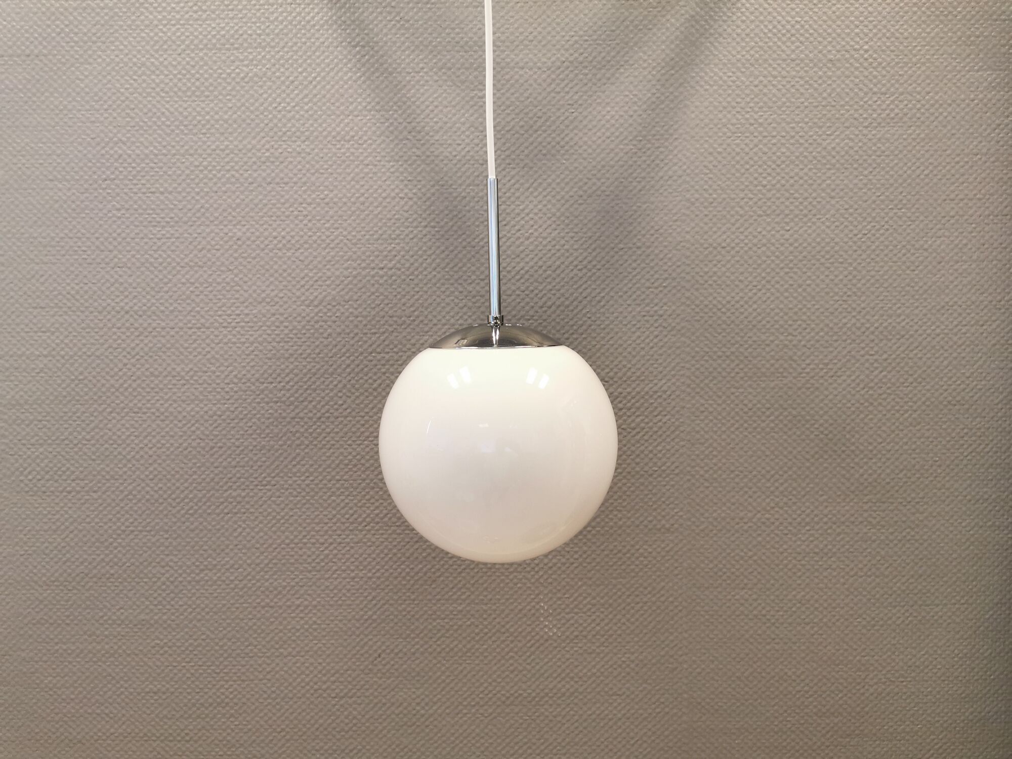 White hanging lamp with metal suspension, made with ball round opal glass shade.