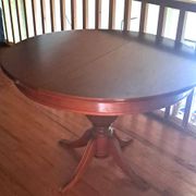 Round solid walnut table with central leg from the 1950s with extensions.
