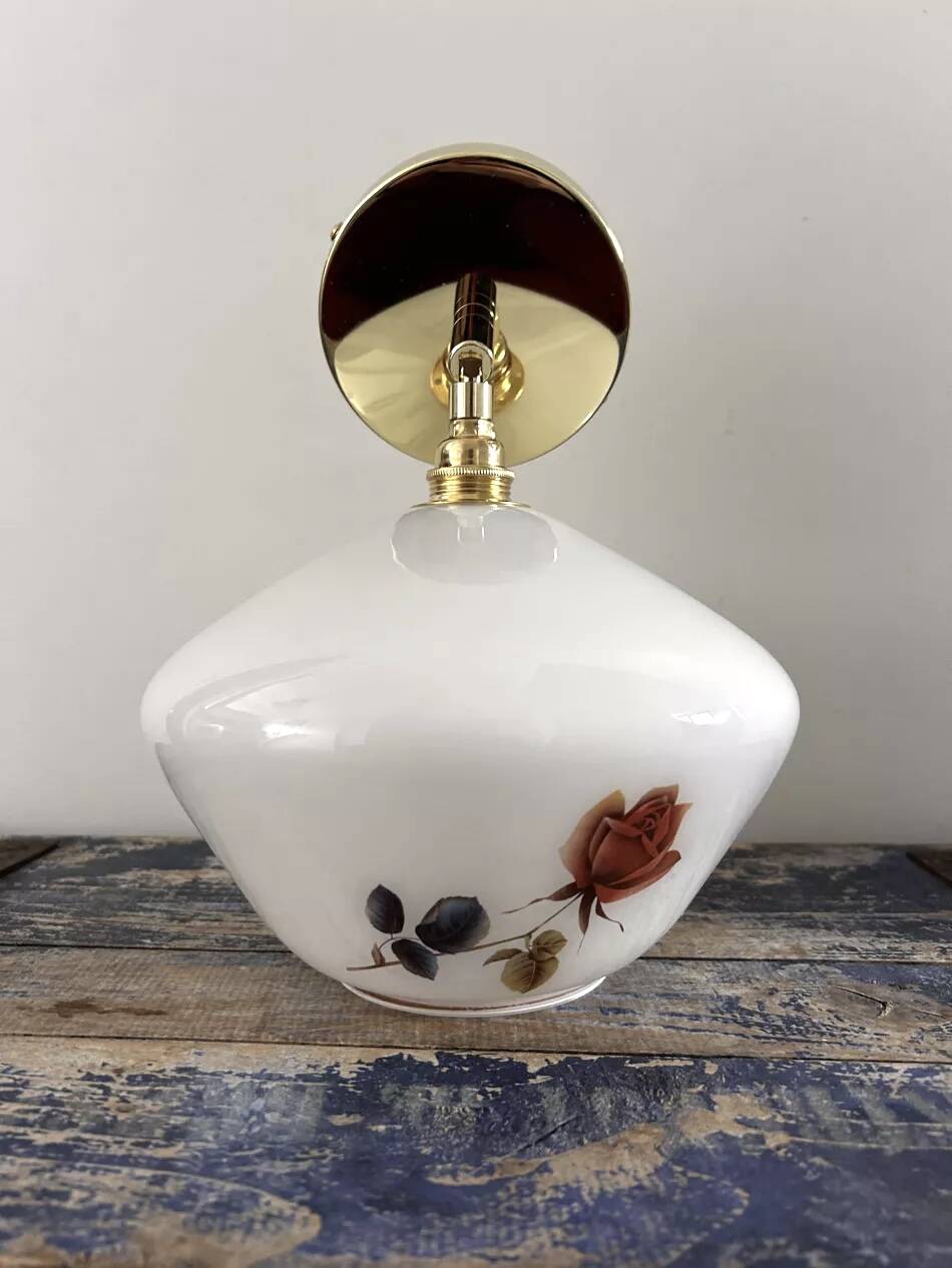 Golden tilting wall light with flowered globe