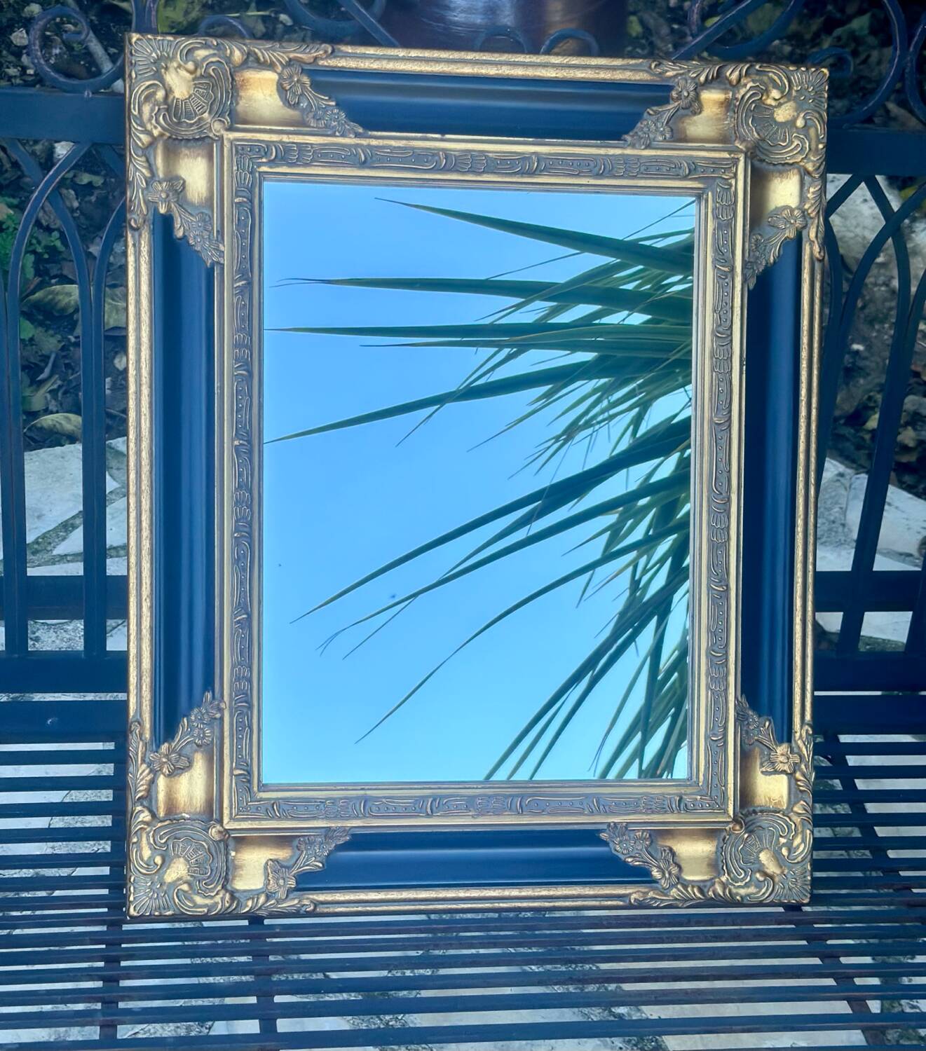 Baroque mirror in gilded wood on a black background.
