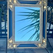 Miroir Baroque en bois doré sur fond noir.