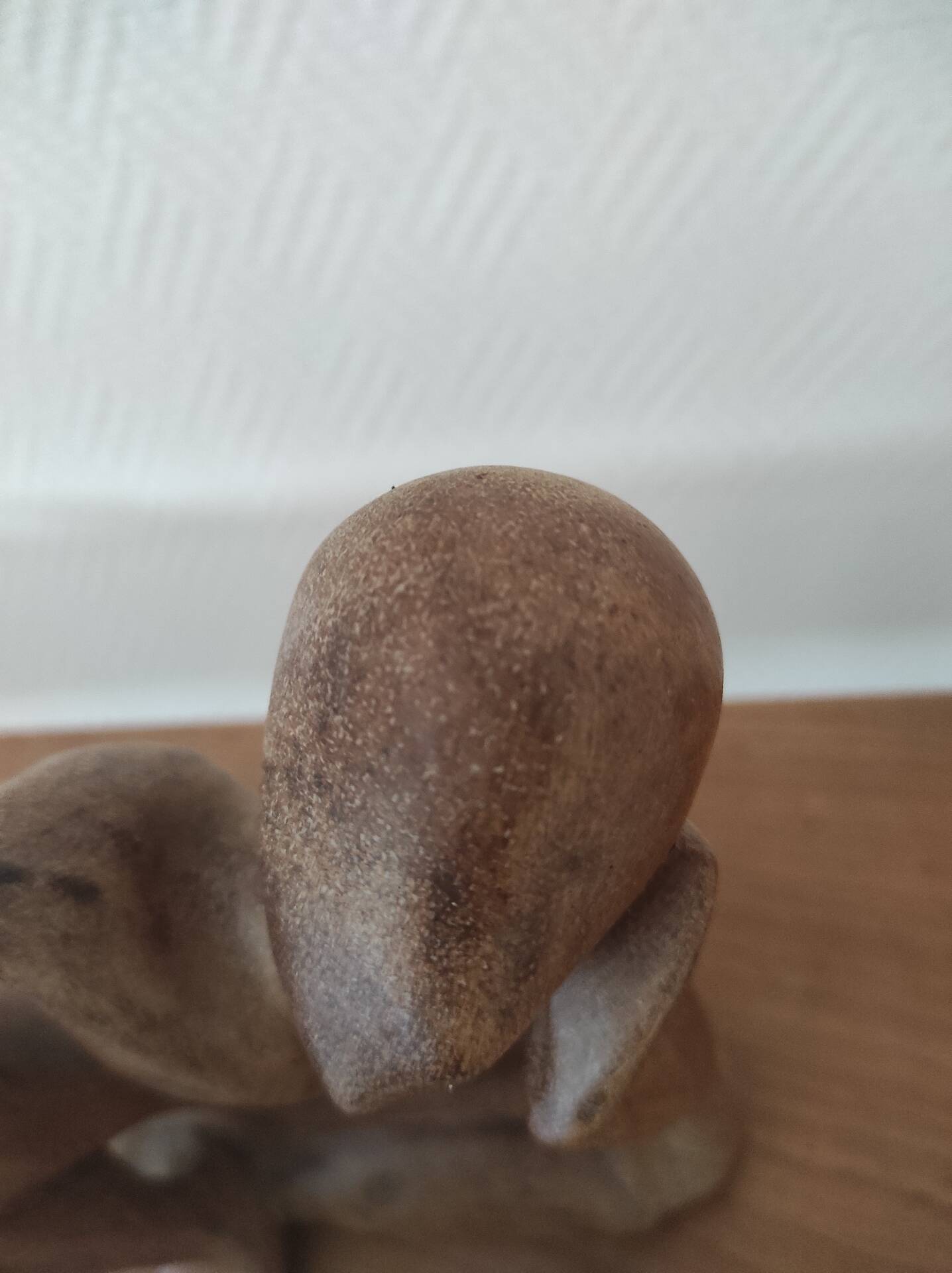 Wooden sculpted statuette of a woman in a pensive pose.