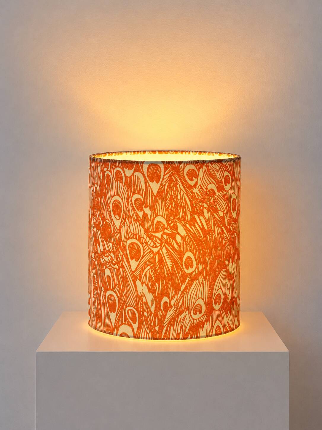 Lampshade covered with a decorative translucent fabric featuring a peacock pattern.