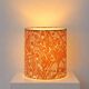 Lampshade covered with a decorative translucent fabric featuring a peacock pattern.