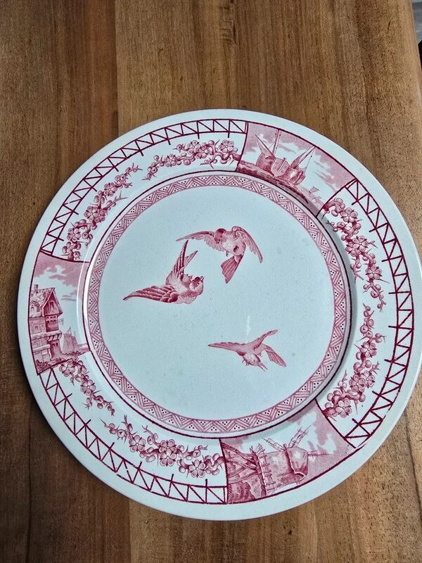 A pair of old flat plates with red and blue bird patterns.