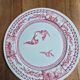 A pair of old flat plates with red and blue bird patterns.