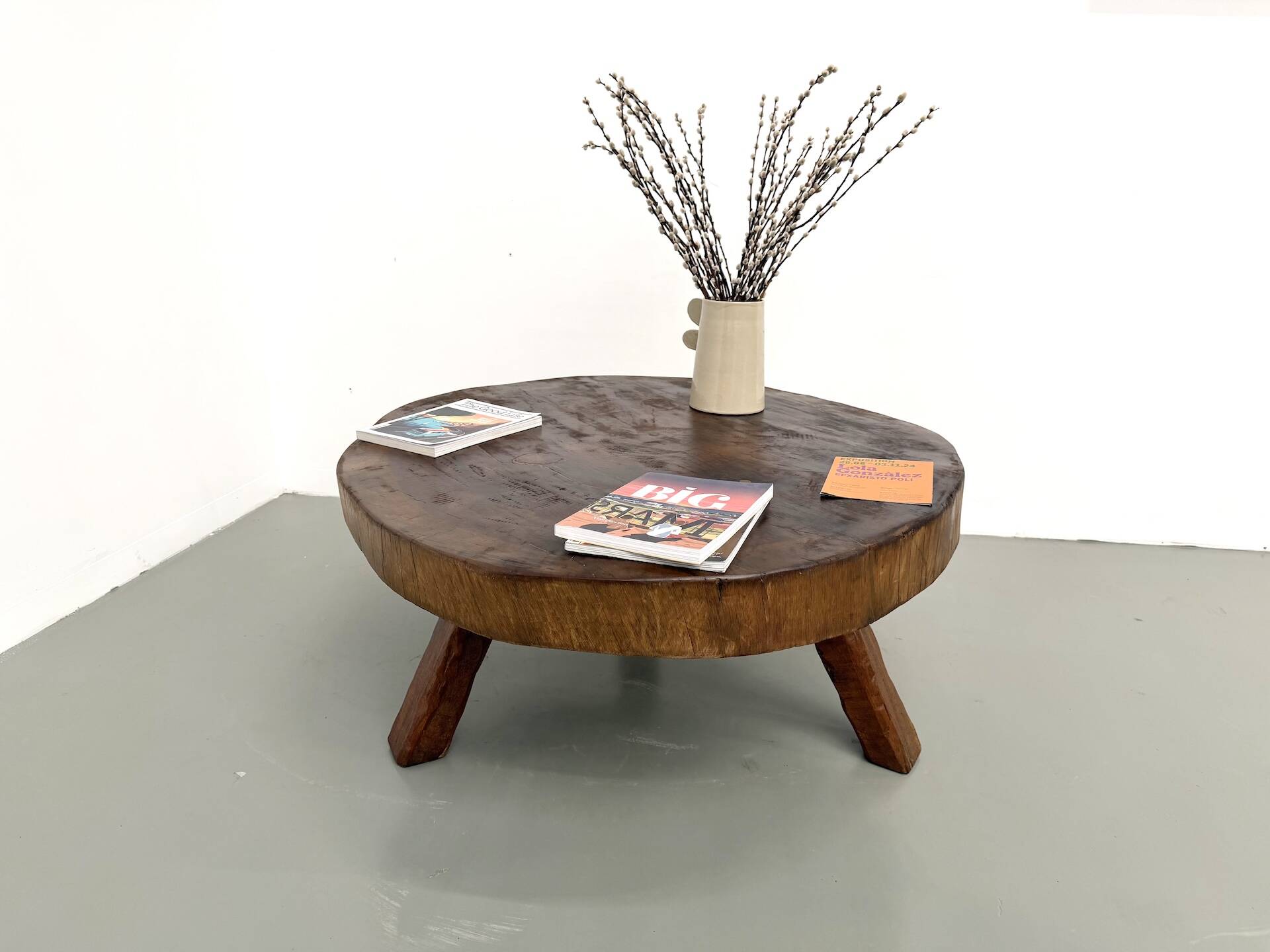 Brutalist coffee table in solid teak, monolithic slab, tripod base.