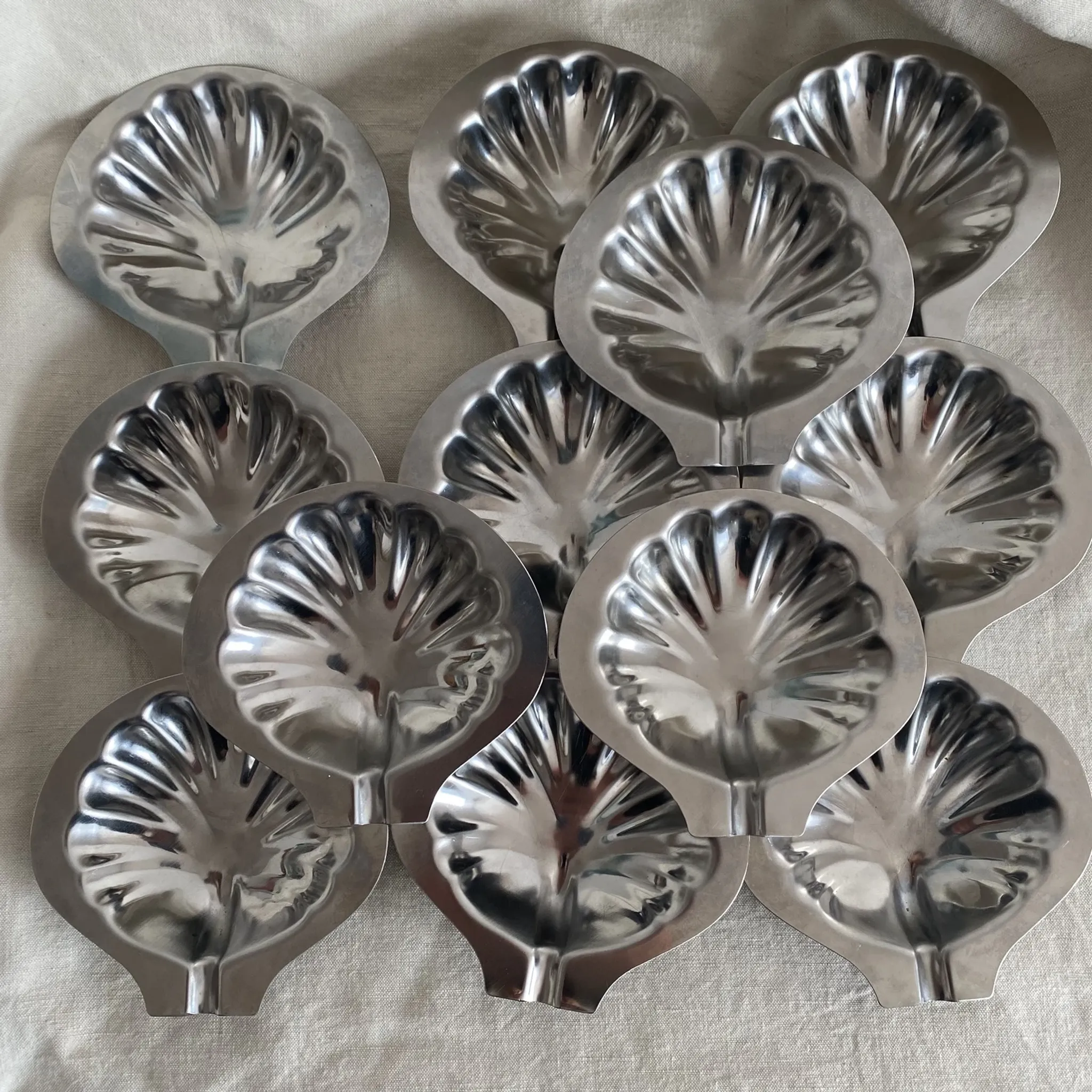 Set of 12 stainless steel scallop shells, 1970s-80s.