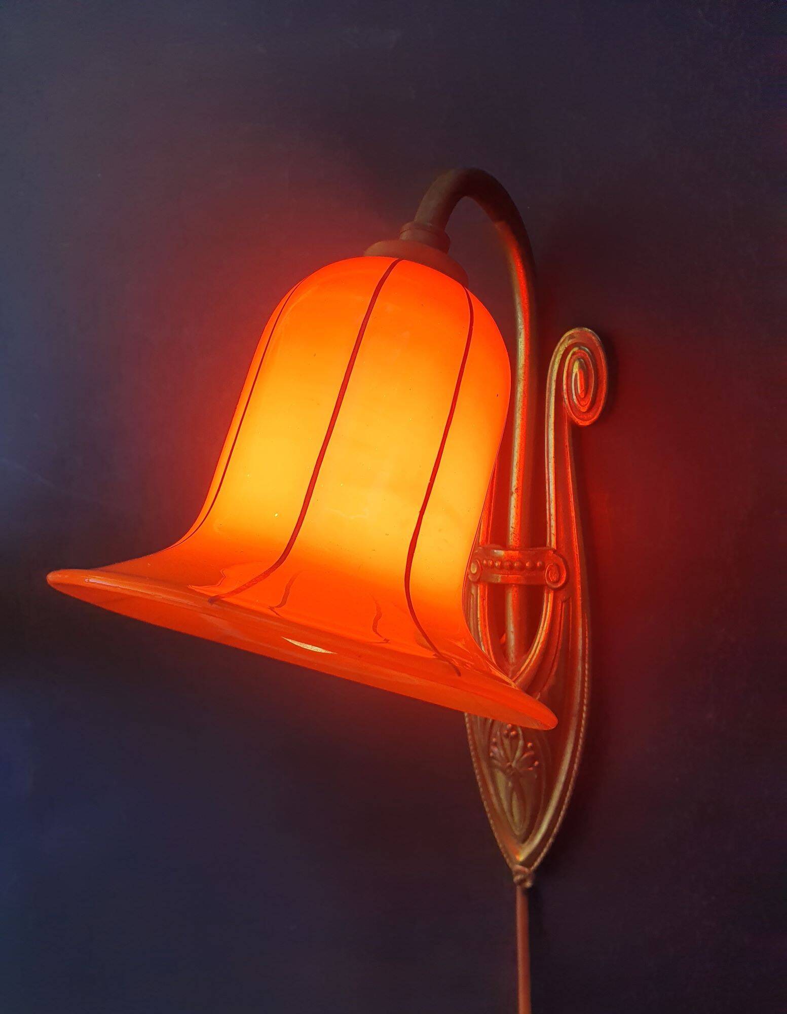 Art Deco wall light in brass with an orange globe.