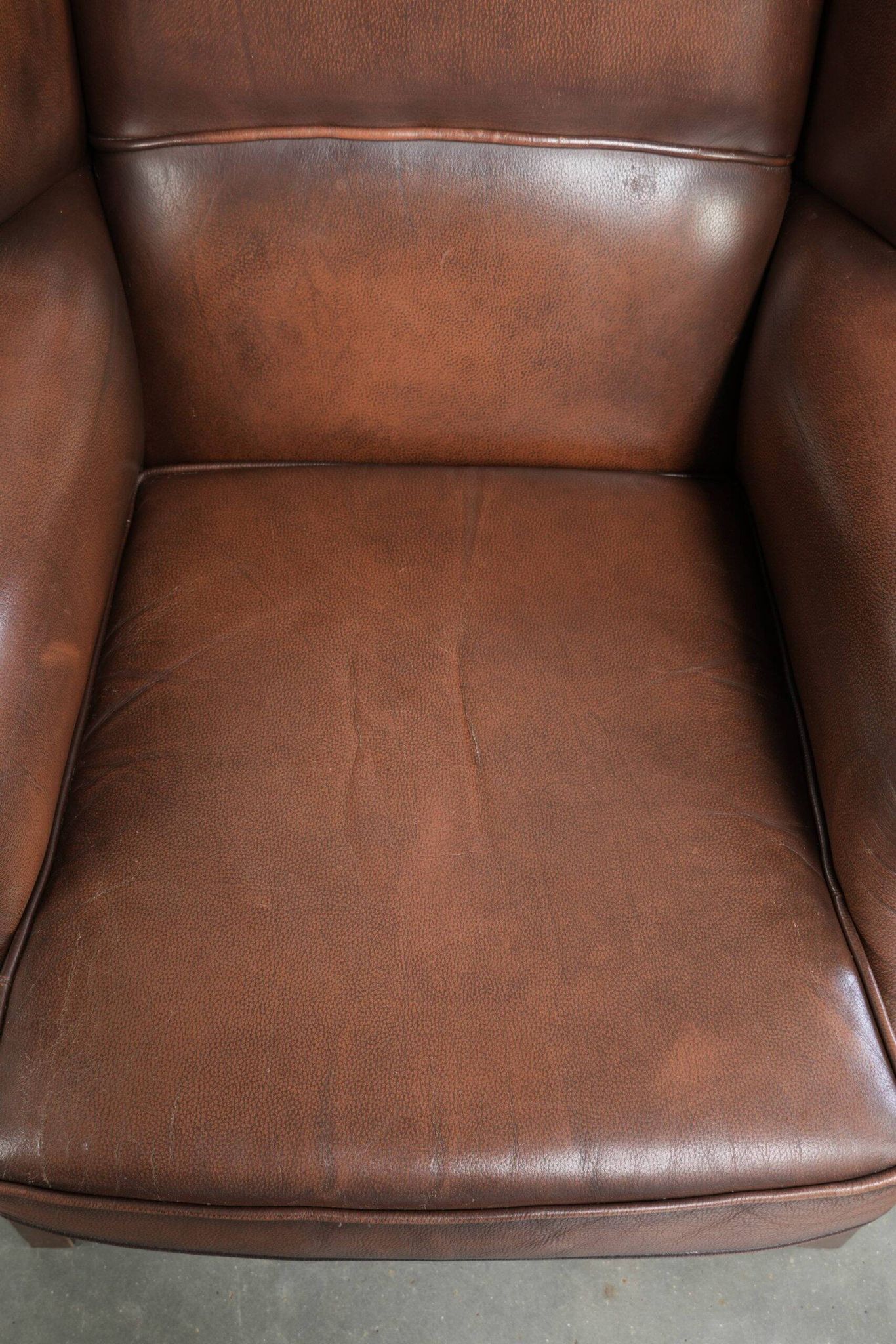 Fauteuil à oreilles en cuir de vache confortable de style anglais avec un look intemporel.