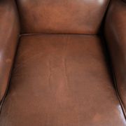 Fauteuil à oreilles en cuir de vache confortable de style anglais avec un look intemporel.