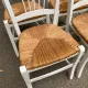 Set of 4 rustic white wooden chairs with straw seats.
