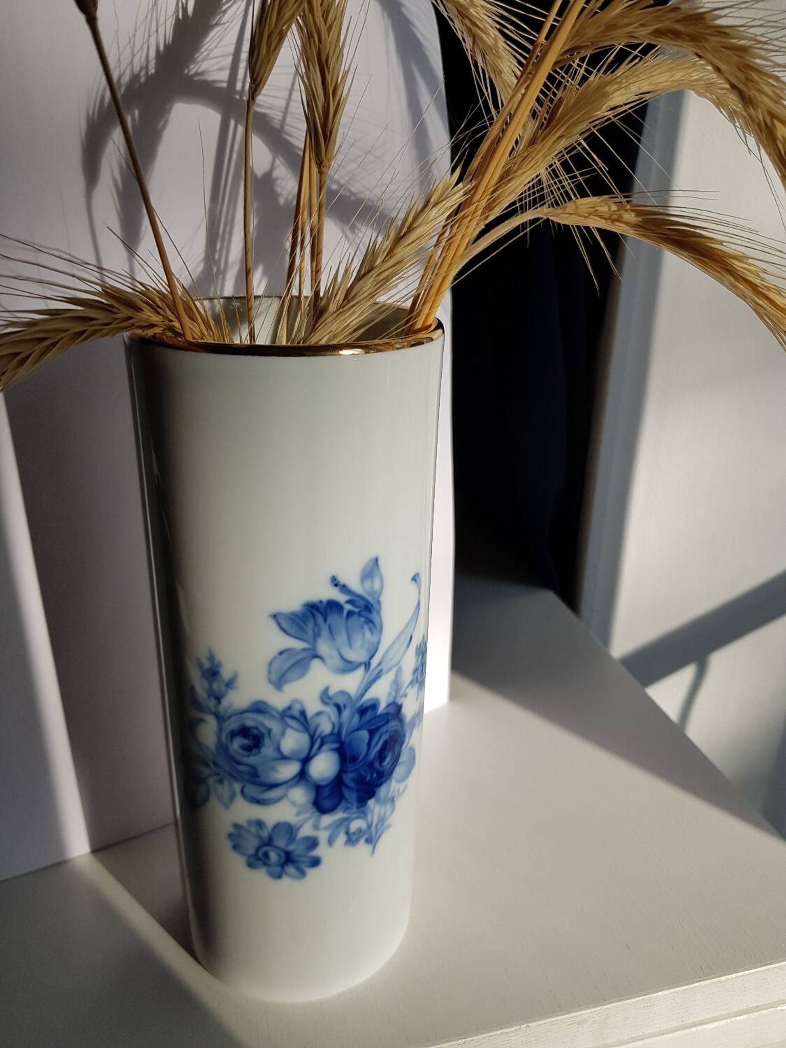 White porcelain vase from Limoges with blue decoration and gold rim.