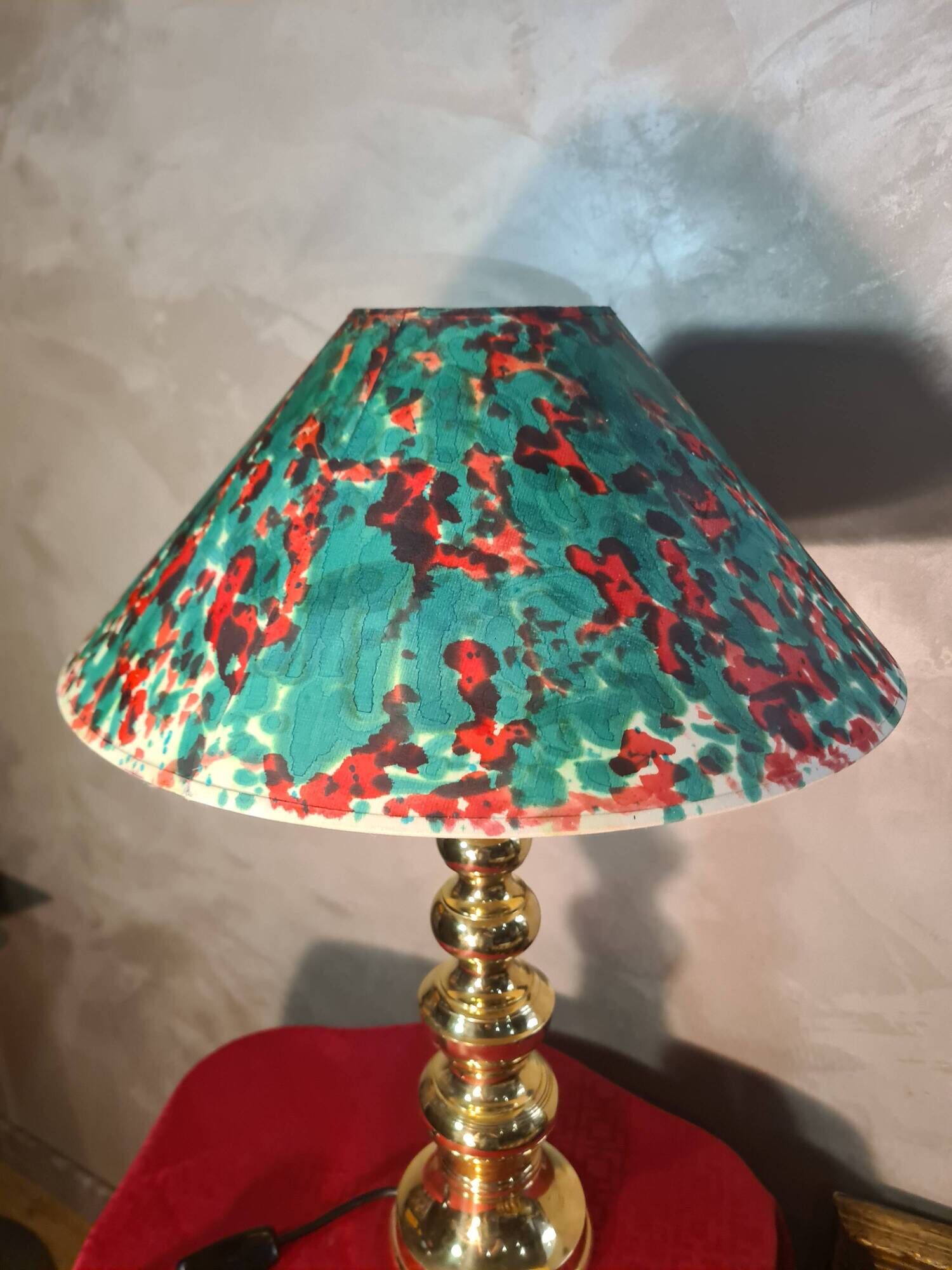 This elegant table lamp features a sculptural base in shiny gold brass.