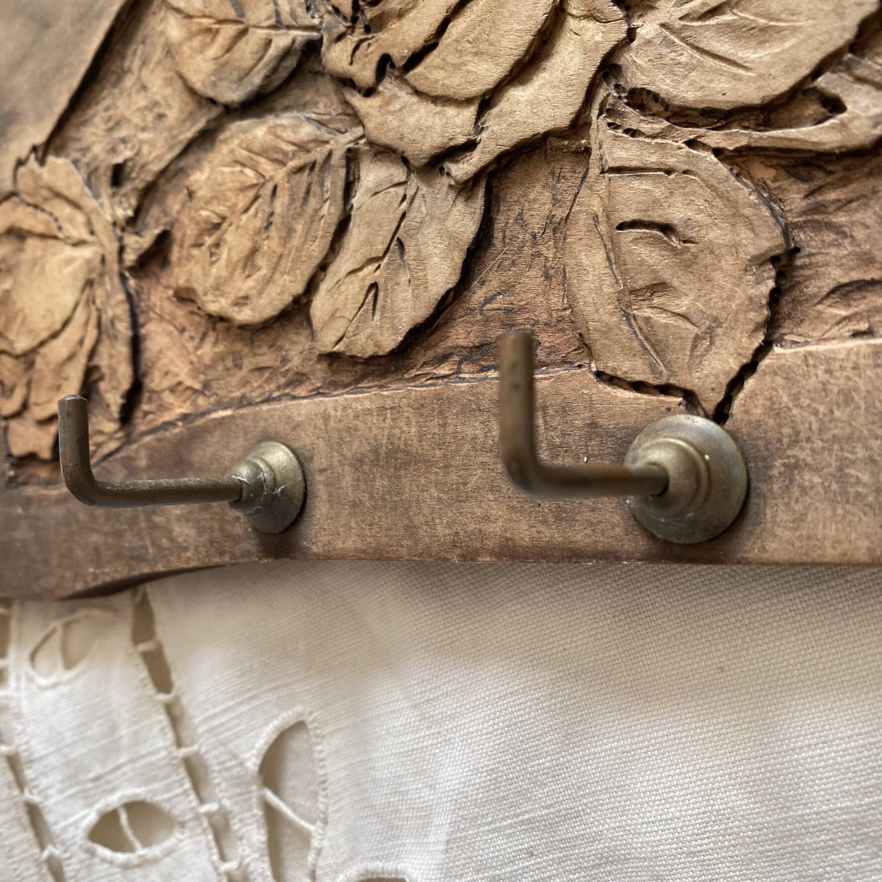 Wall-mounted coat rack in carved wood with rose decoration.