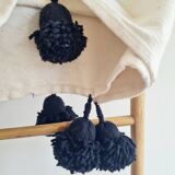 Handwoven throw with black stripes and pom-poms