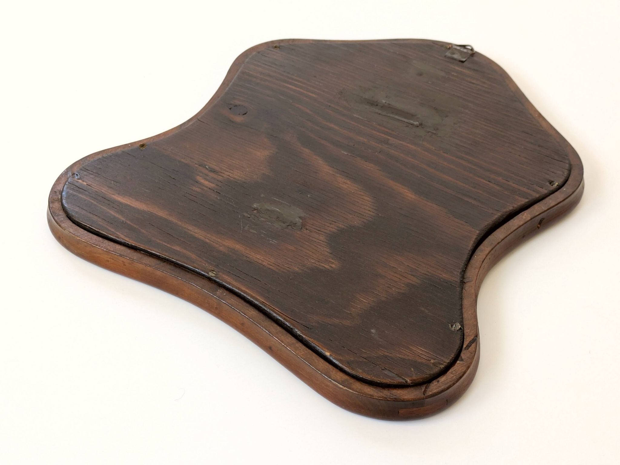 Antique wall mirror in carved wood with a wavy shape and a golden trim.