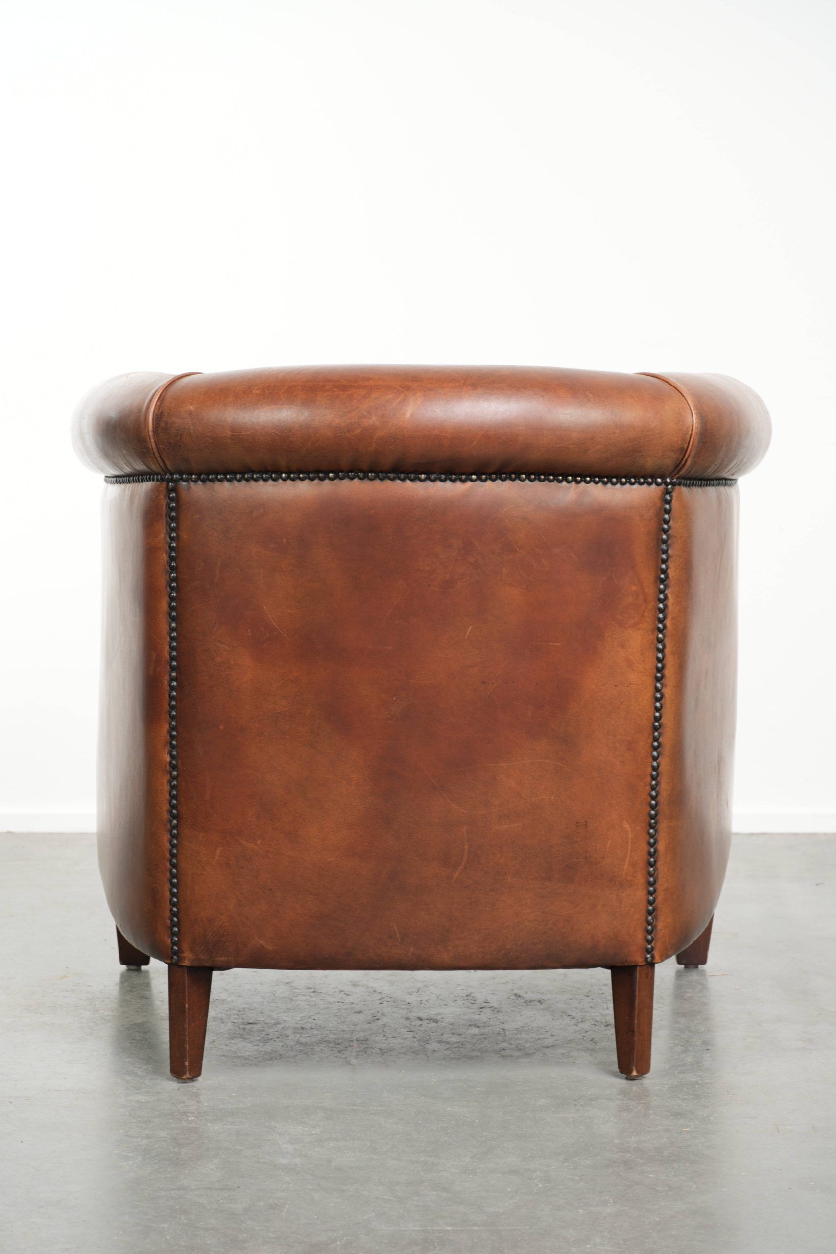 Sheepskin club armchair with a cognac colour finished with decorative nails