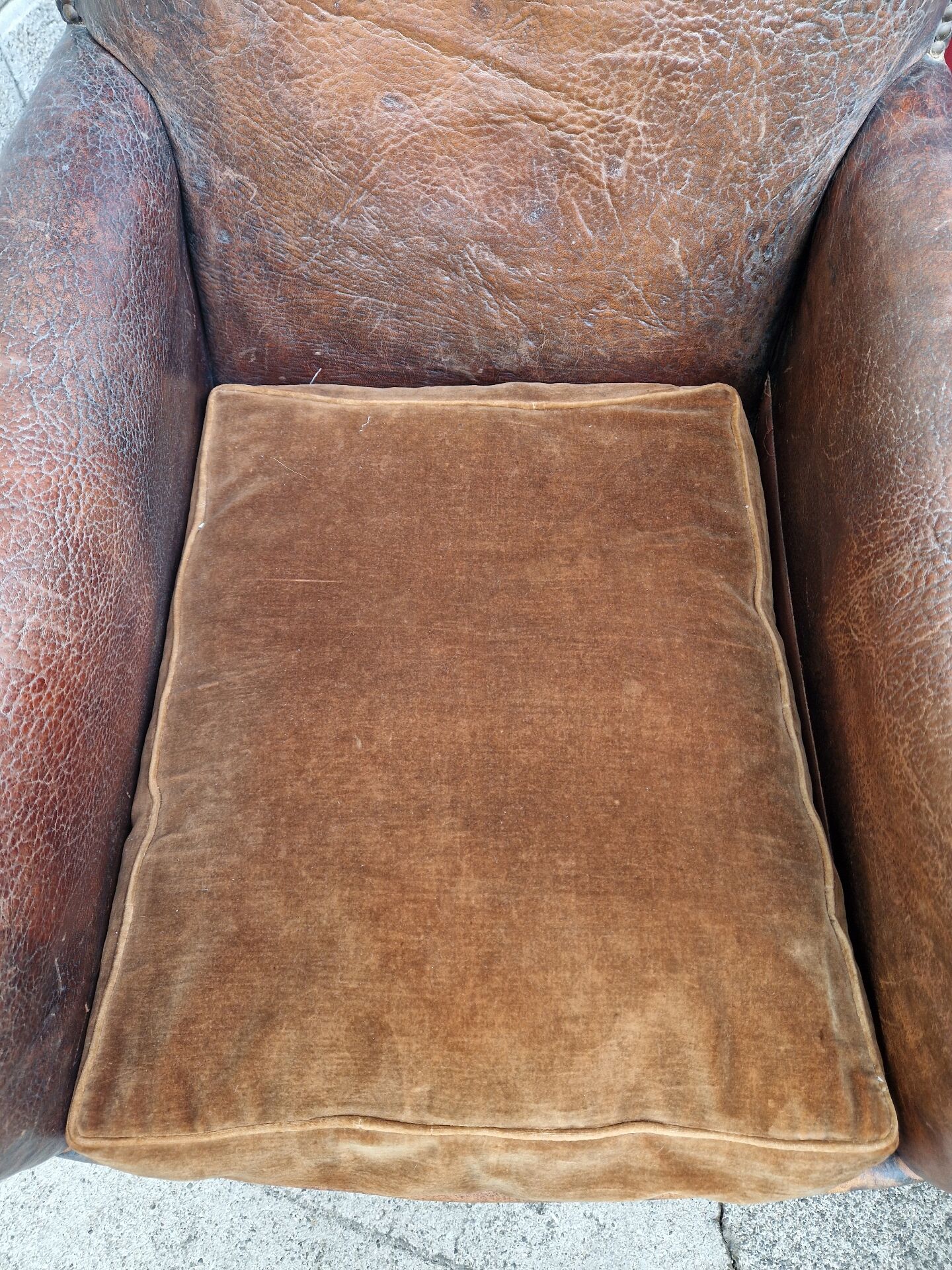 Antique club chair in patinated brown leather, early 20th century English style.
