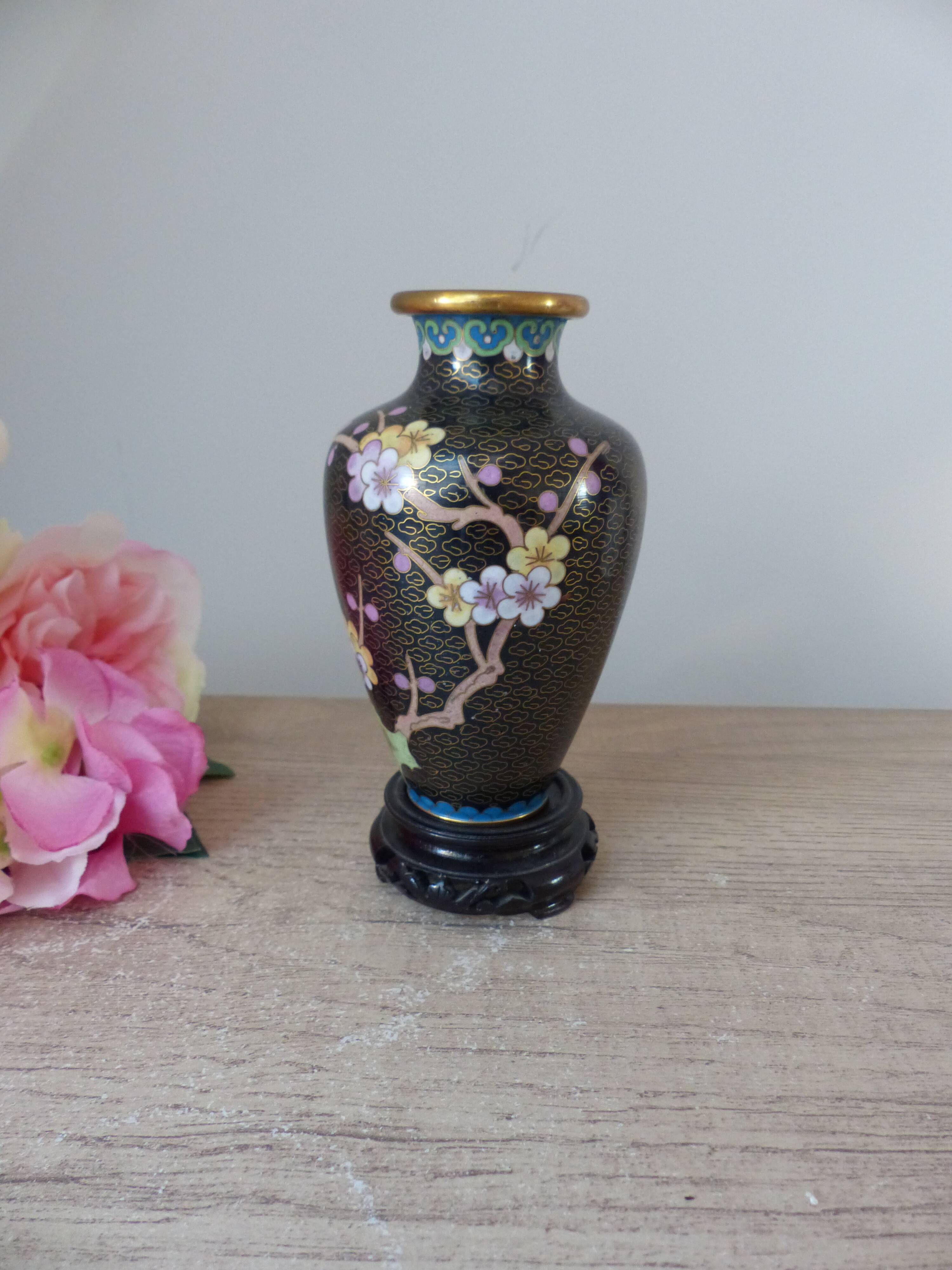 Small black cloisonné vase decorated with yellow and pink cherry blossoms, vase on wooden base