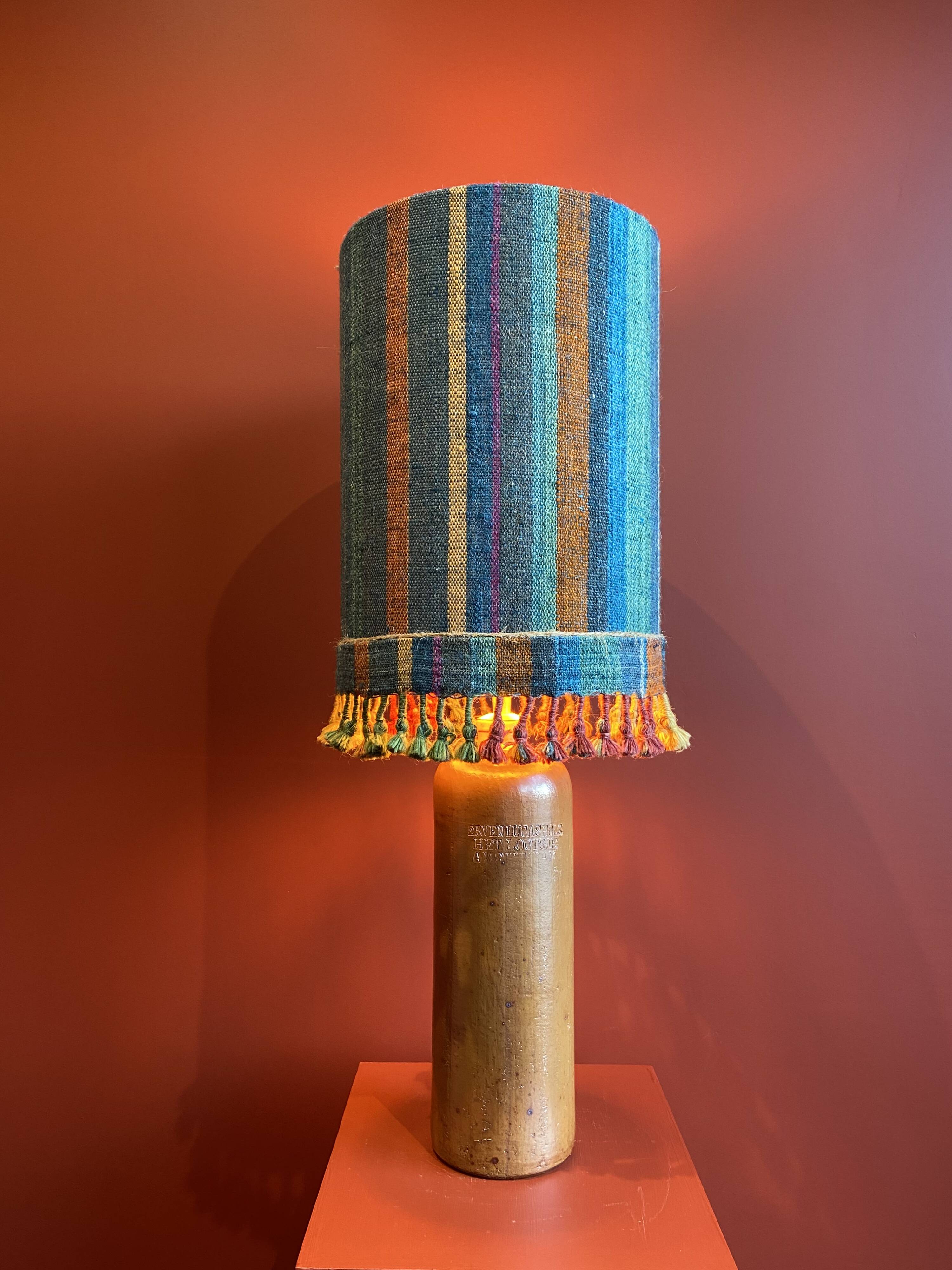 "Stoneware Bottle Lamp" with a multicoloured blue lampshade handwoven in India.