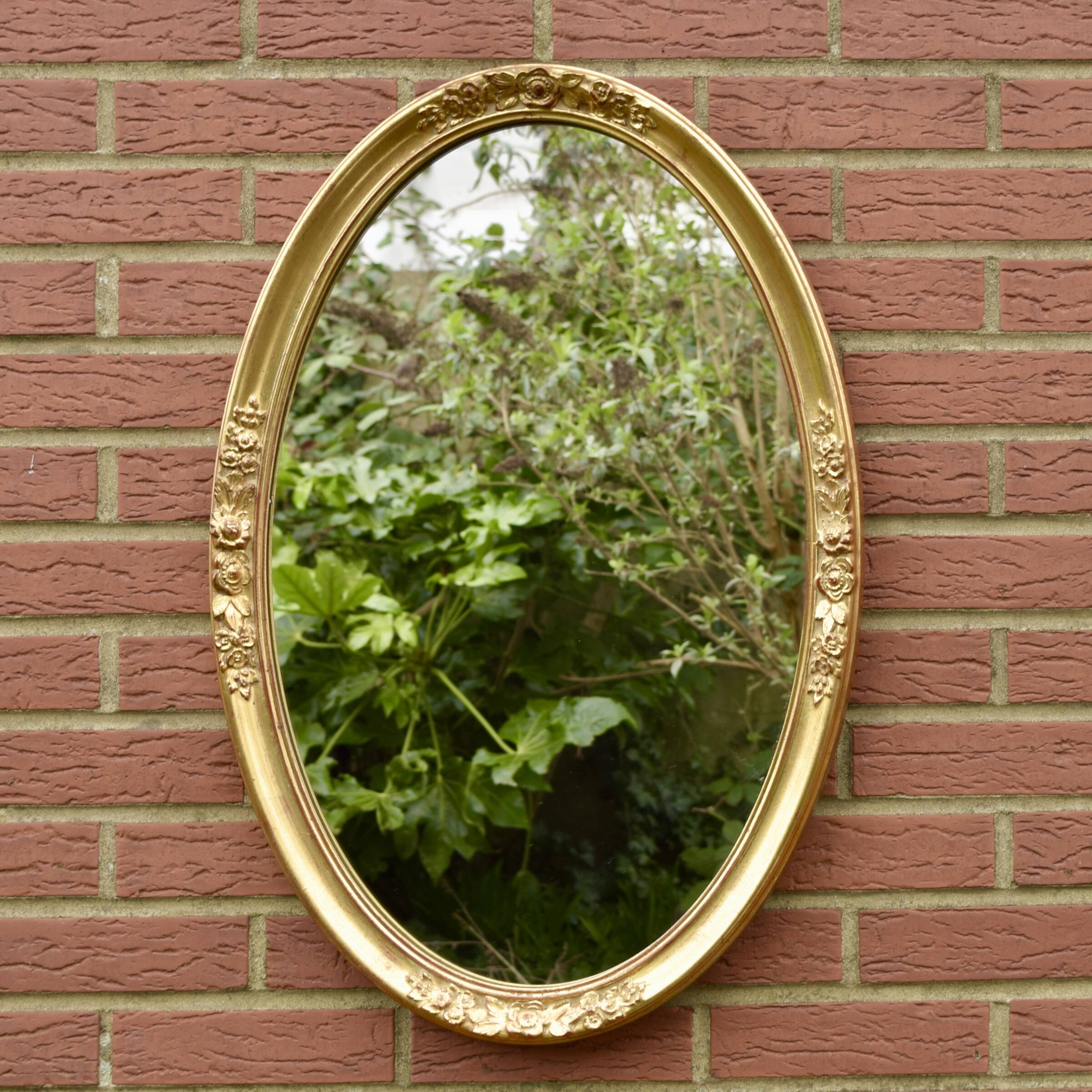 Old large oval wall mirror in golden resin