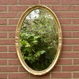 Old large oval wall mirror in golden resin