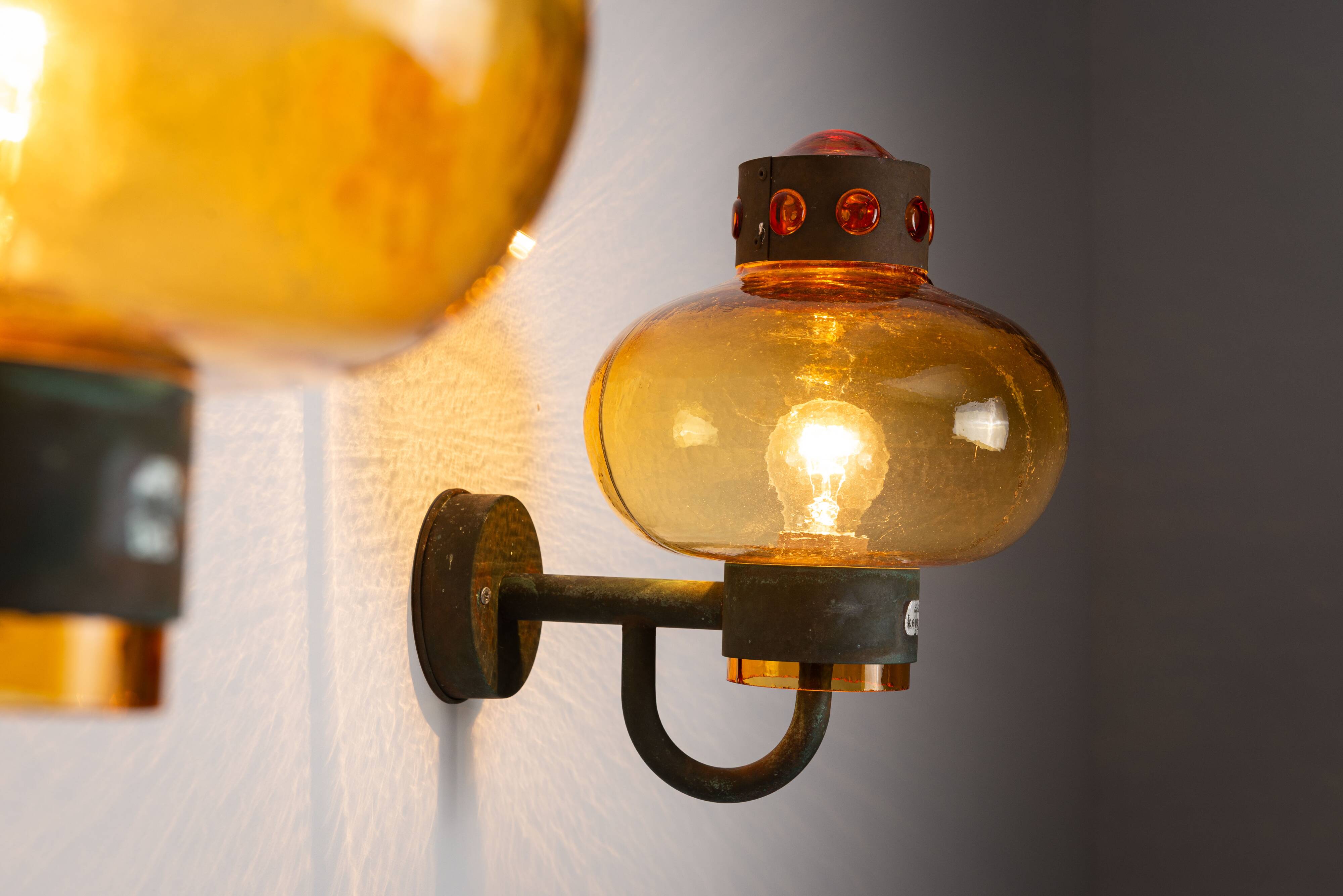 Pair of brass wall lamps with decorated amber coloured shades