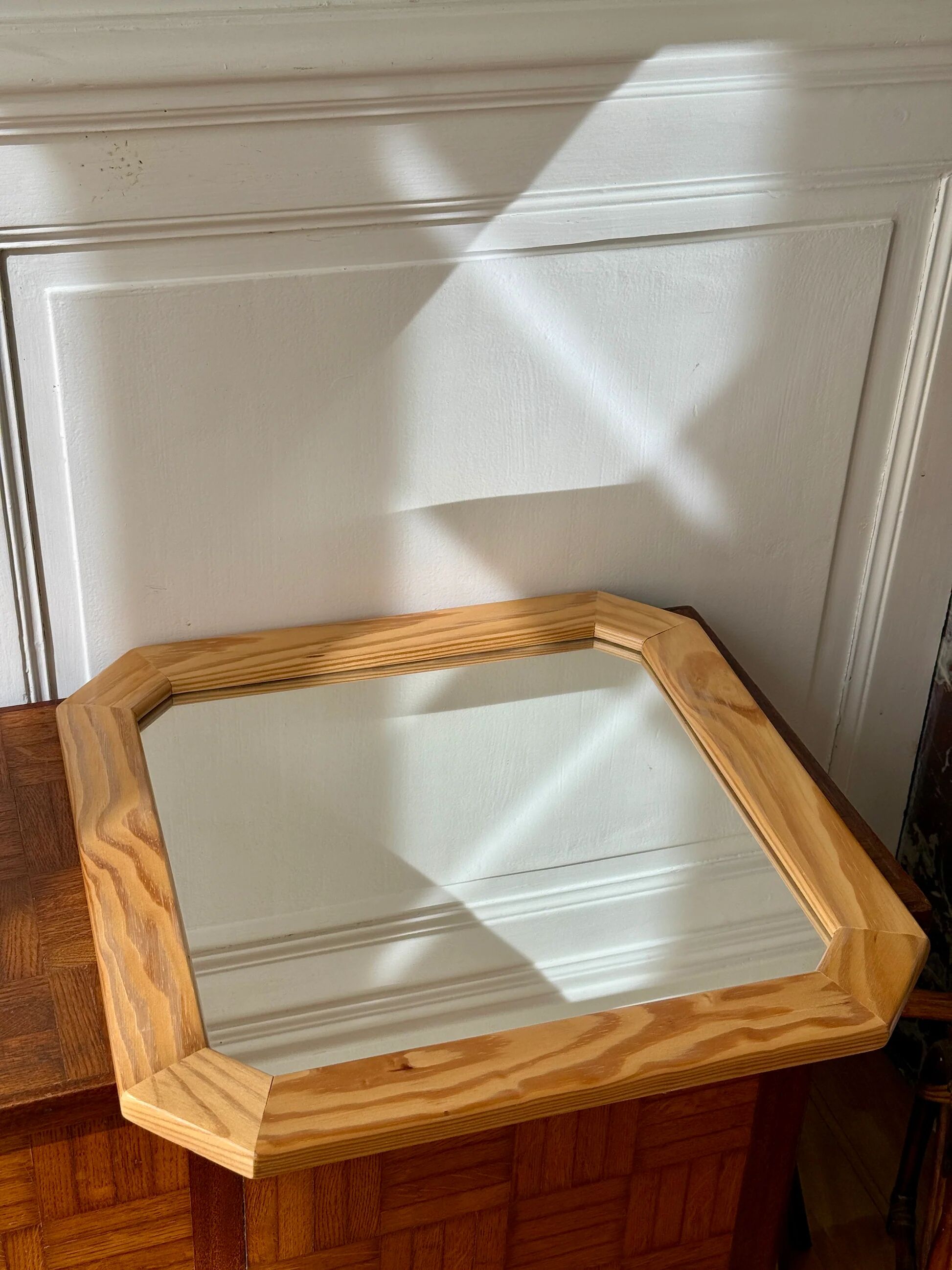 Octagonal mirror in light wood with grooves.