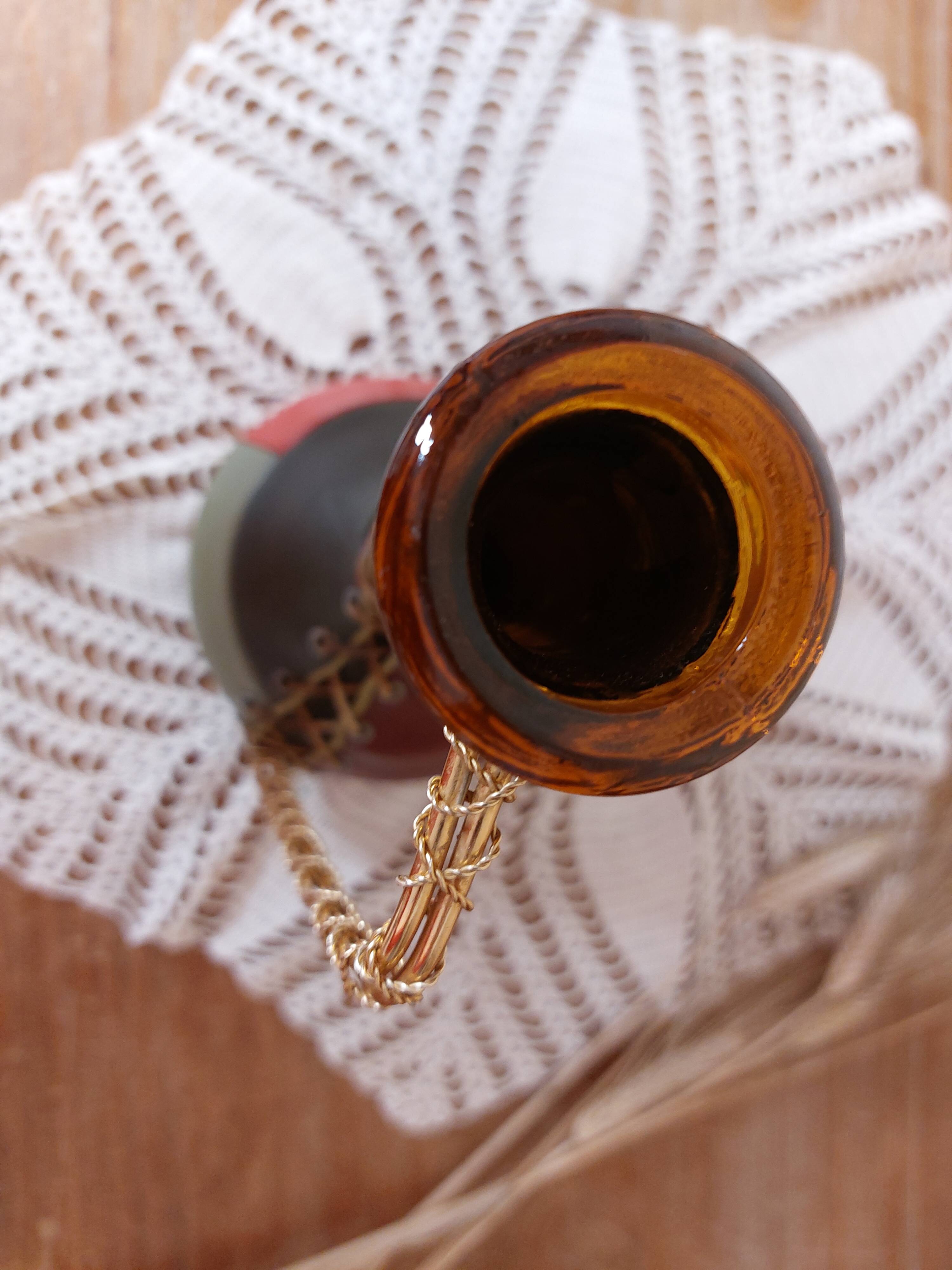 Amber bottle covered in colored leather with handle surrounded by wire, vintage