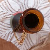 Amber bottle covered in colored leather with handle surrounded by wire, vintage