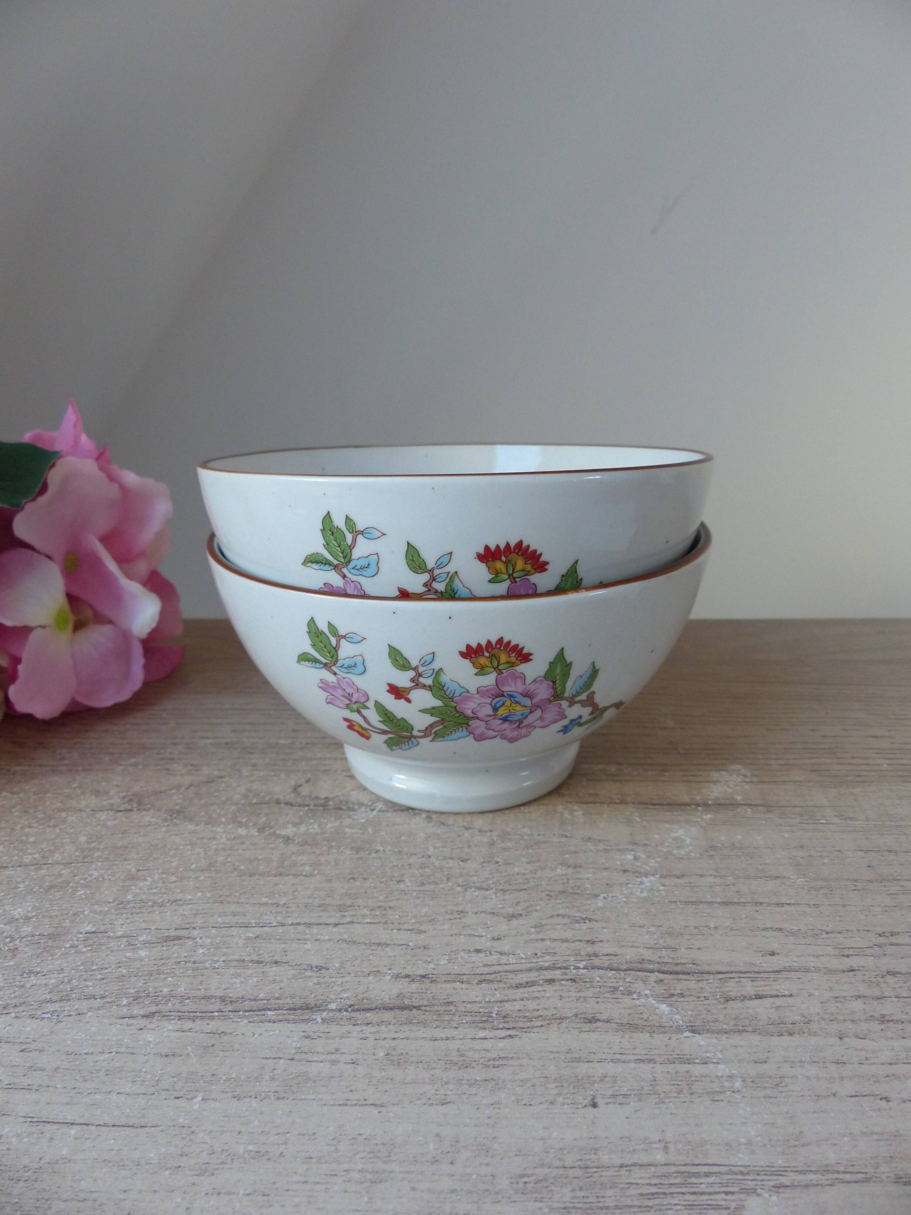 Two speckled beige ceramic breakfast bowls with pink flower decoration