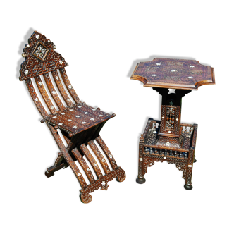 A folding chair and a carved Syrian table with 19th-century mother-of-pearl inlays.