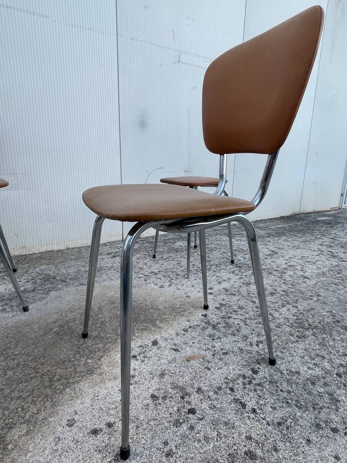 3 chairs and a vintage stool in faux leather and tubular design.