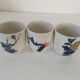 Set of three hand-painted porcelain cups with floral patterns.