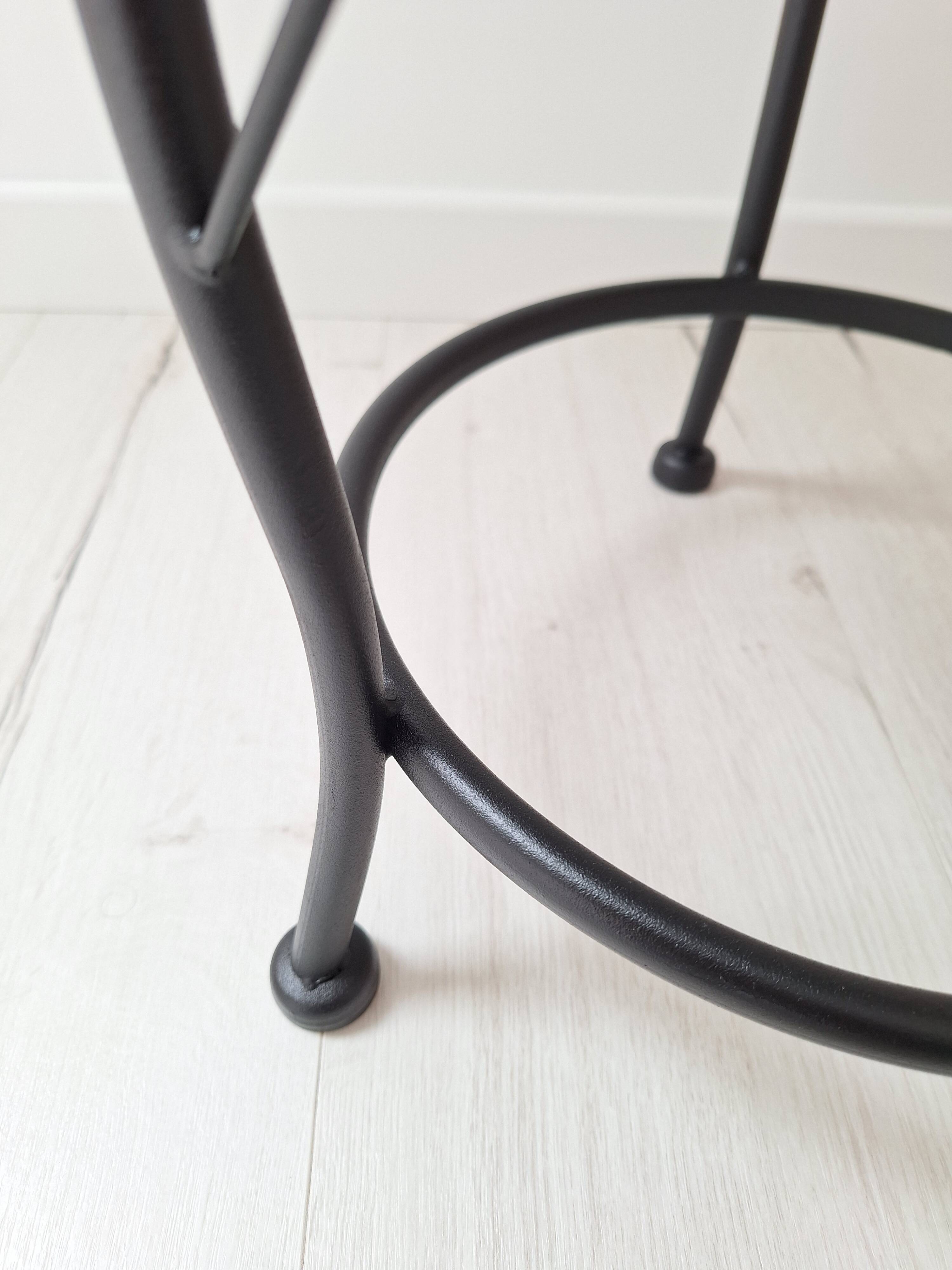 Black iron stool/pouf with its boucle fabric cushion.